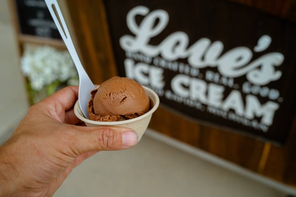 A person is holding a cup of ice cream from Love's Ice Cream truck.